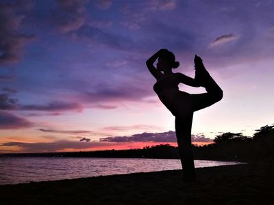 Silhouette of a person in a balancing yoga pose.